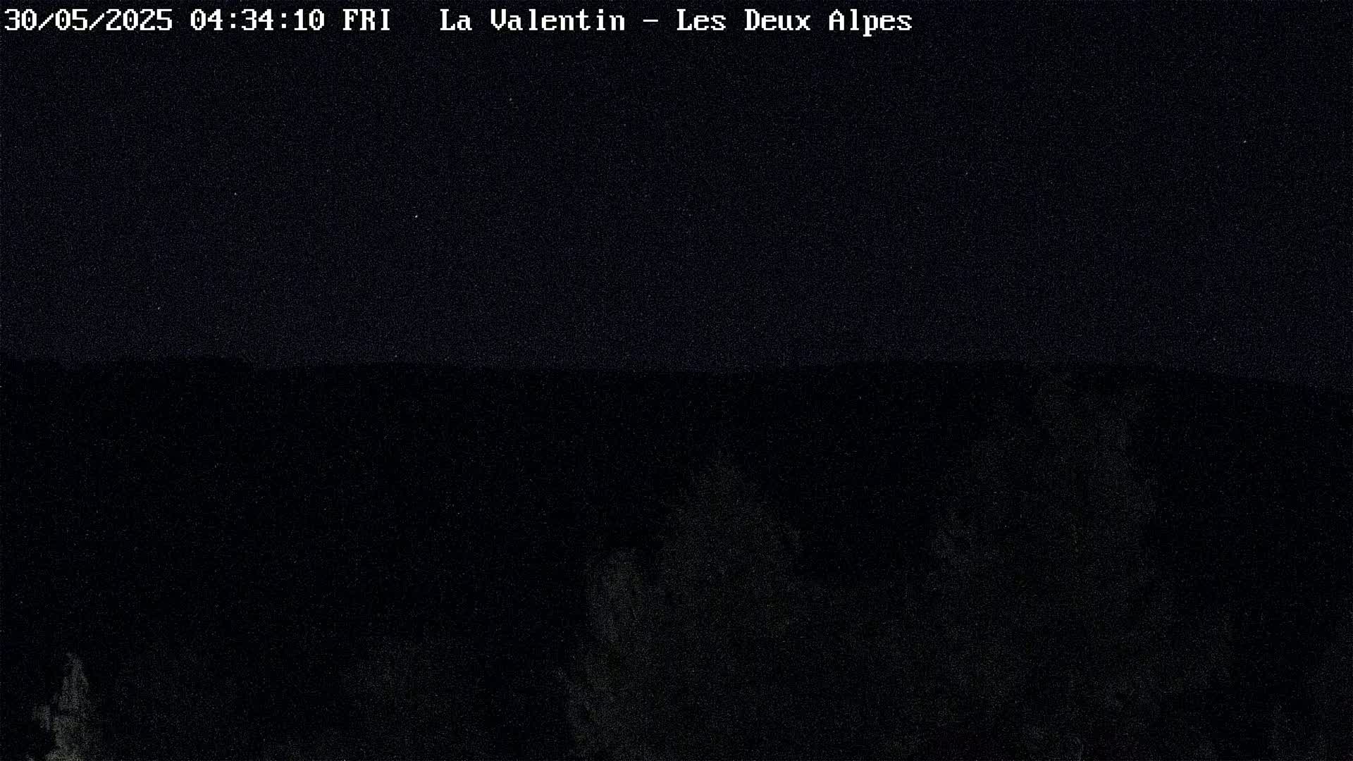 A dark, nighttime image shows a mostly obscured landscape under a clear, starlit sky.