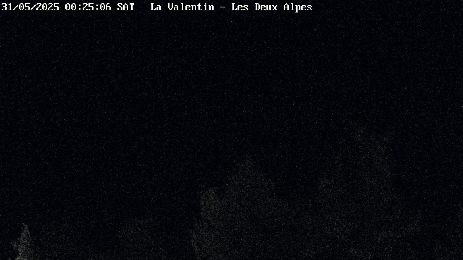 A nighttime image shows a dark sky with faint, indistinct shapes possibly representing trees or mountains in the lower portion of the frame.