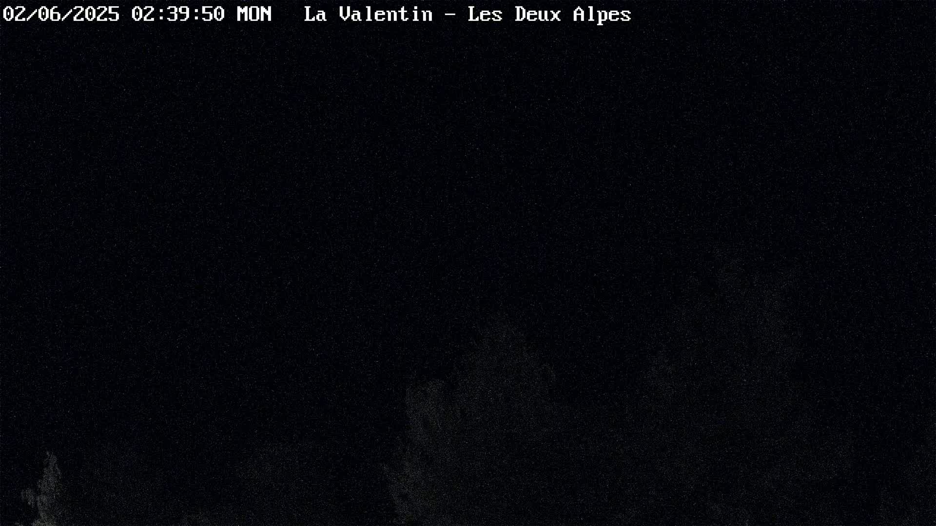 A dark, nighttime scene shows a mostly black sky with faint, indistinct shapes suggesting trees or vegetation in the lower portion.