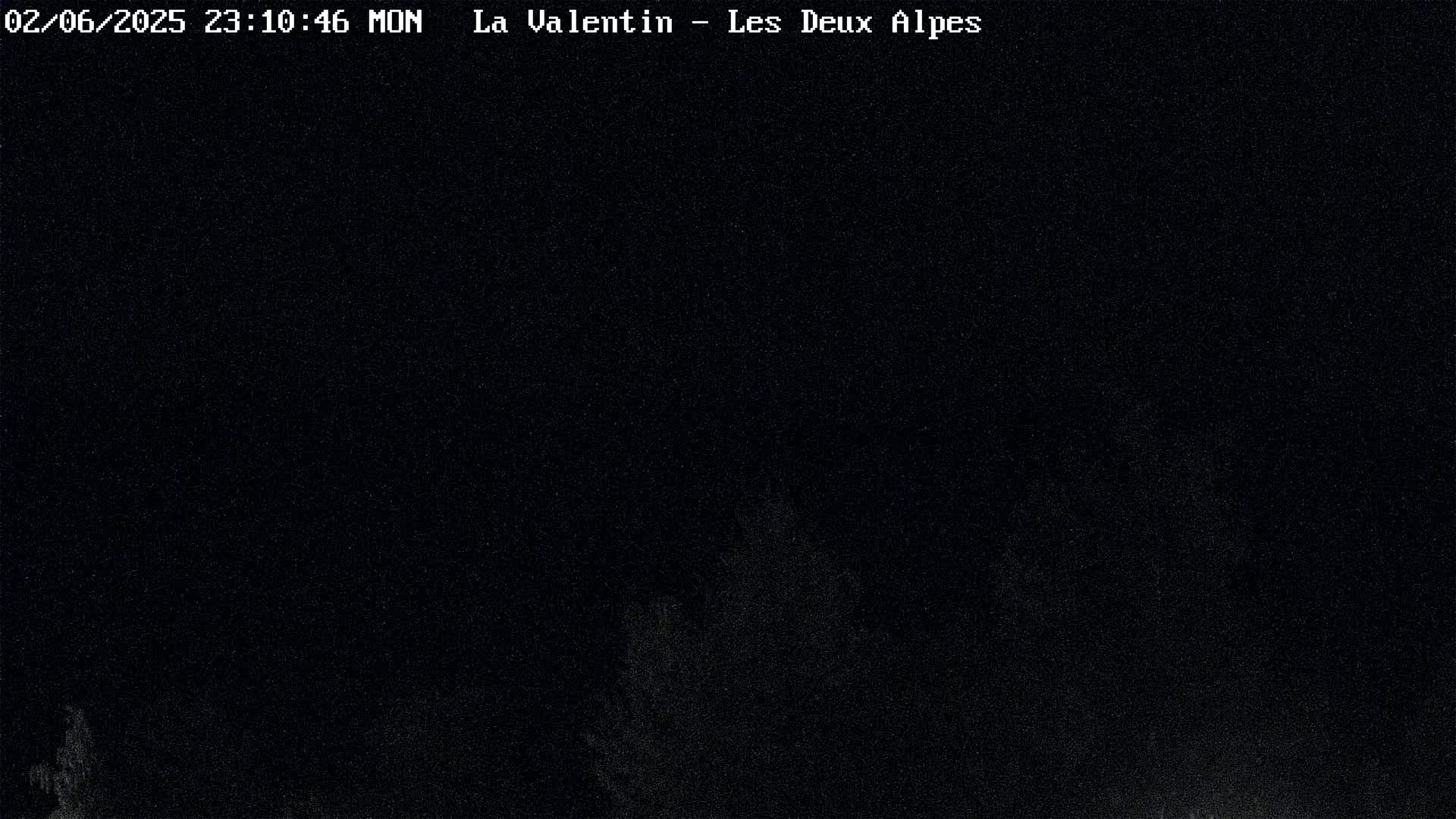 A nighttime, dark image shows indistinct shapes that could be trees or other objects in low light conditions.