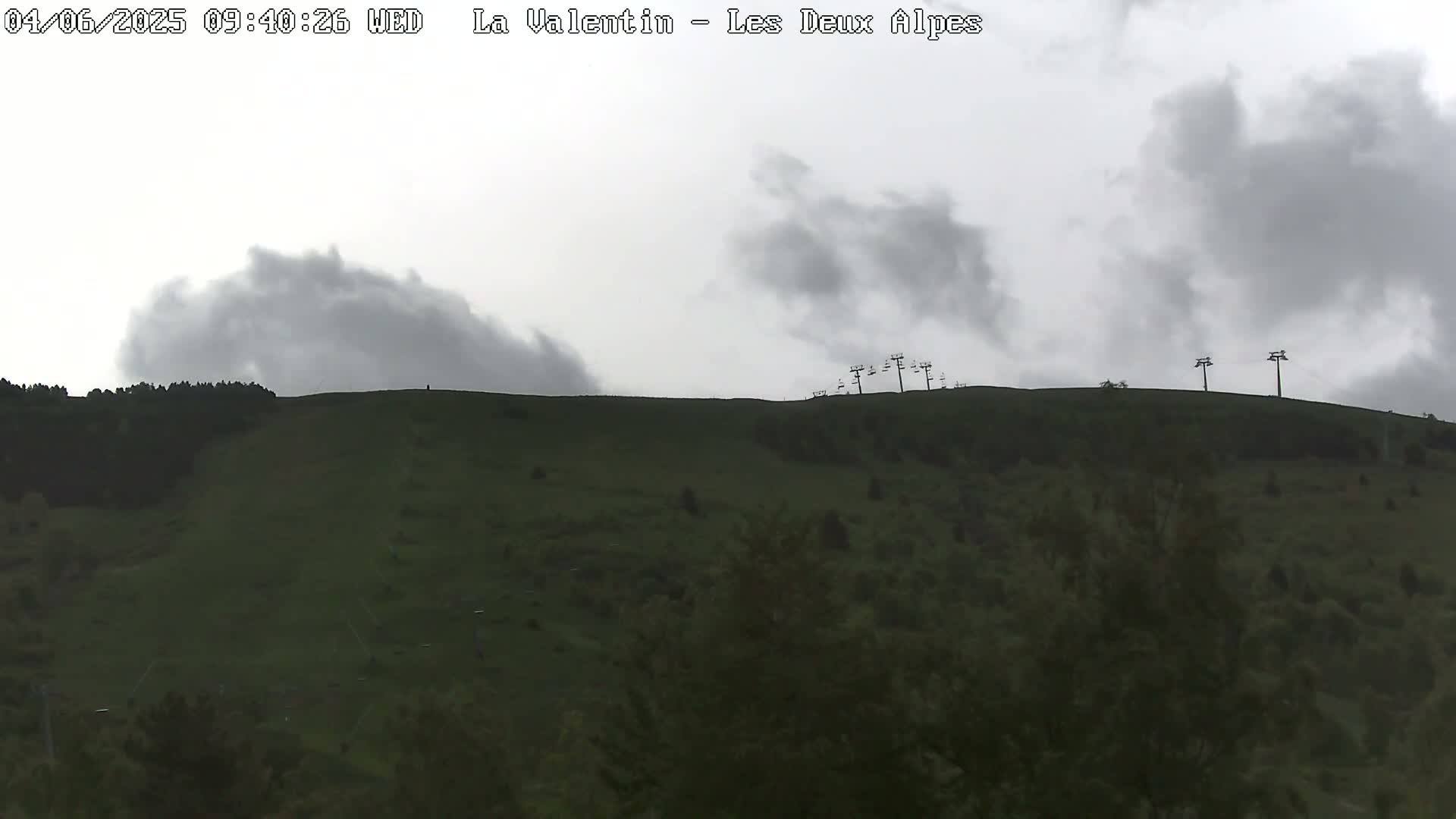 A grassy hill with a chairlift at the top is visible under an overcast sky.