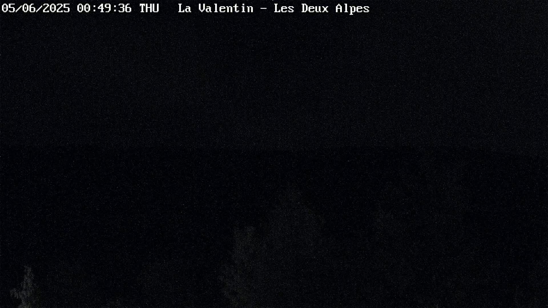 A nighttime, dark image shows a mostly black view with a few barely visible specks of light.