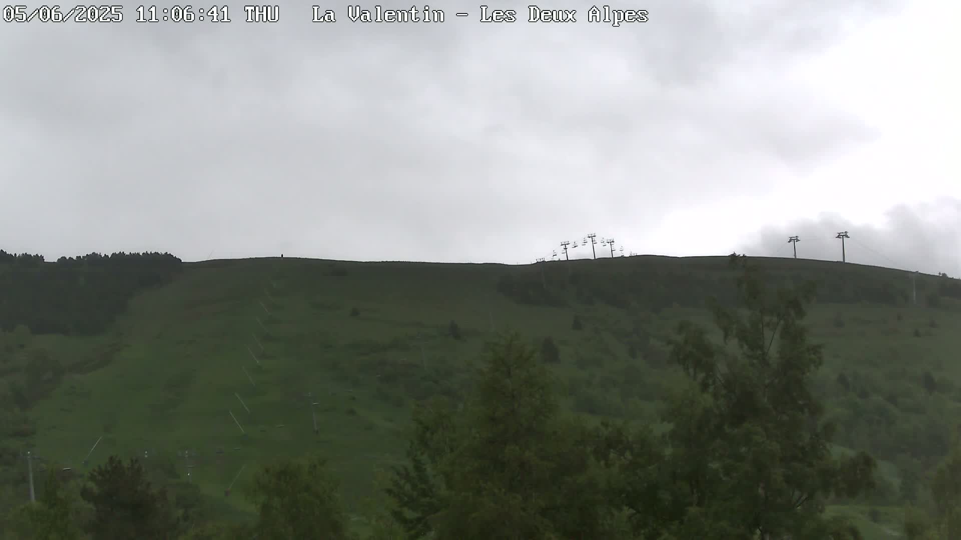 A grassy hillside with several chairlifts is visible under an overcast sky.