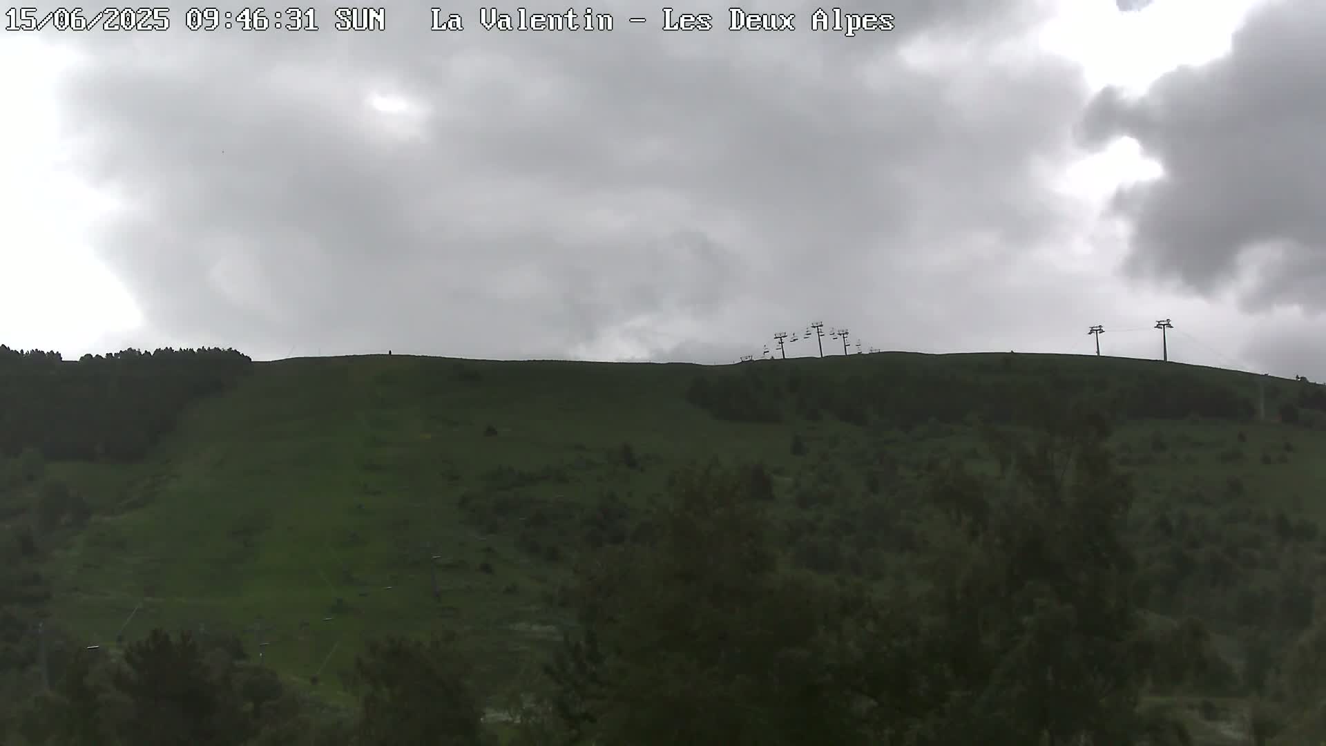 A grassy hillside with a few chairlifts at the top is visible under an overcast sky.