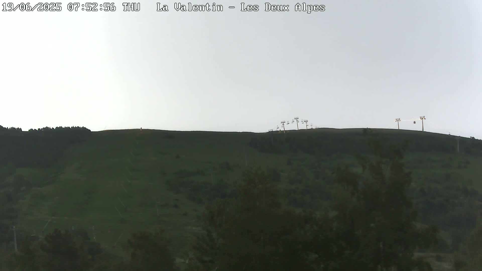 A grassy hillside with a chairlift at the top is visible under an overcast sky.