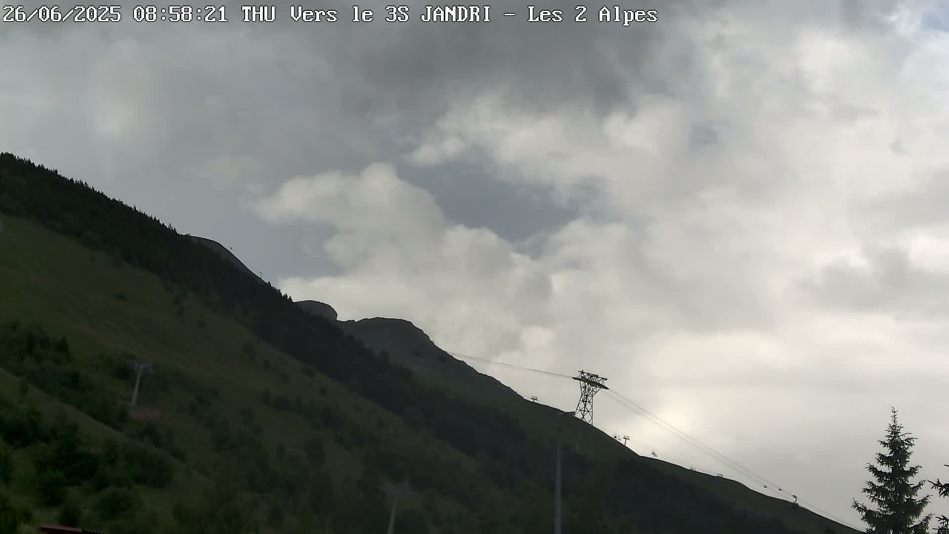 A chairlift ascends a verdant mountainside under a cloudy sky.