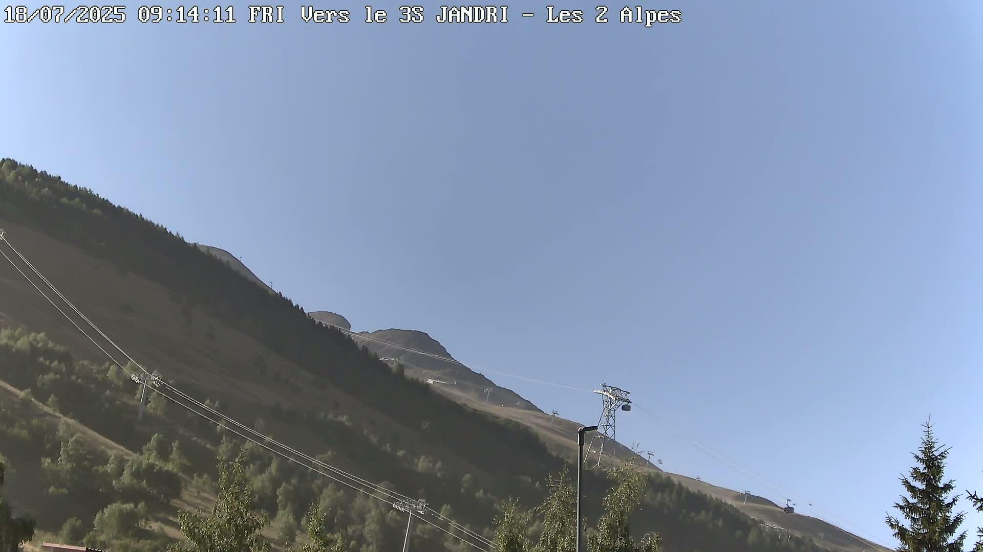 A clear, sunny day shows a mountain slope with a chairlift ascending to the peak.