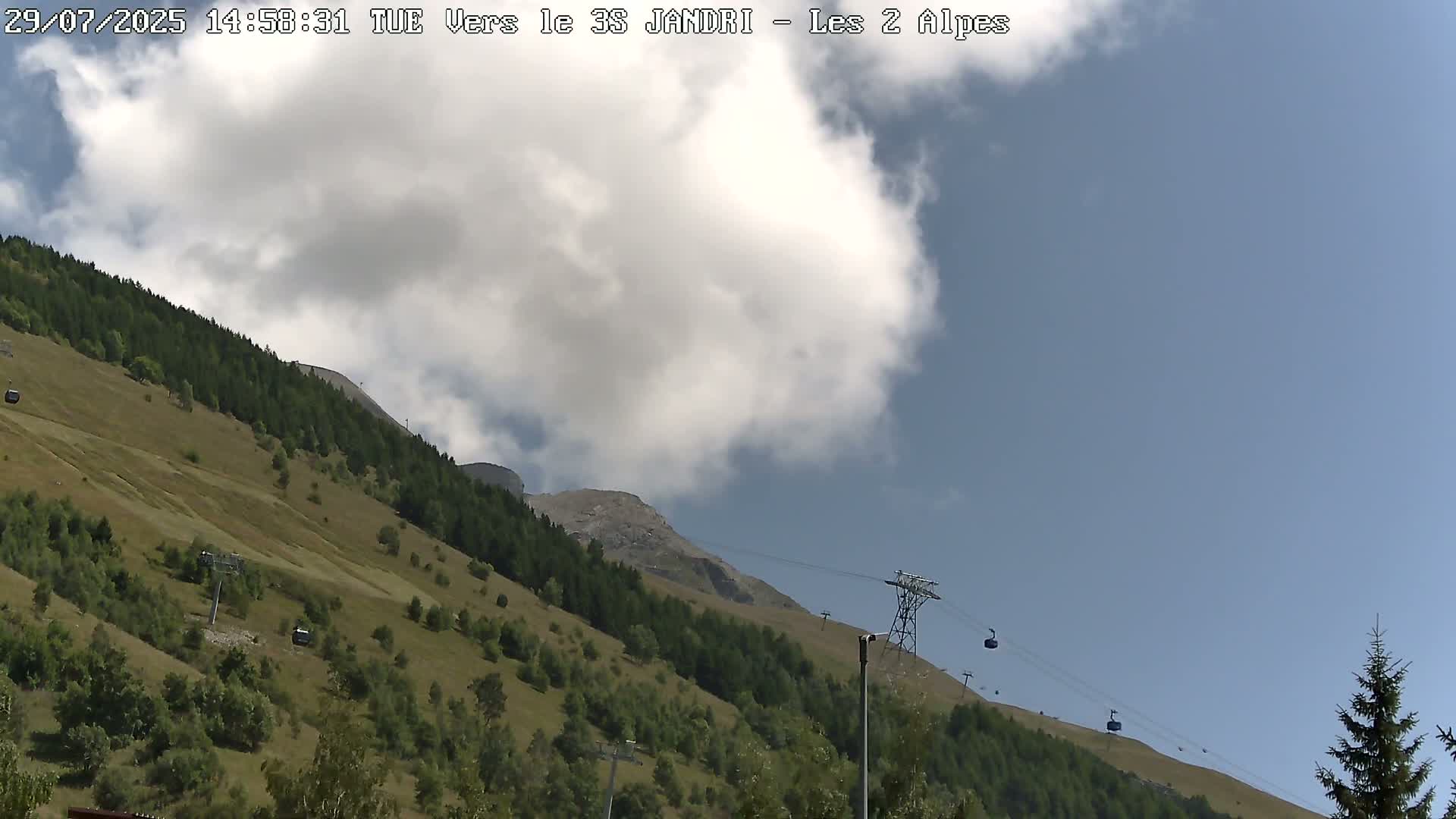 A clear blue sky overlooks a mountain slope with sparse vegetation and a cable car system.