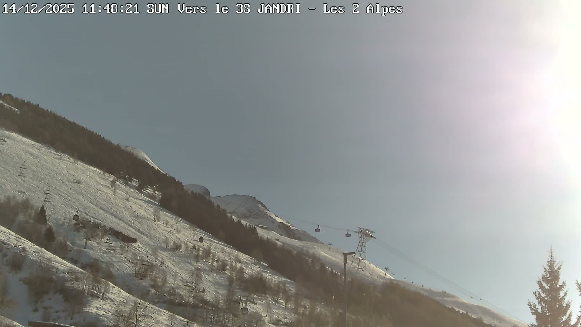 A snowy mountain slope, dotted with bare trees and evergreens, features multiple ski lifts traversing the landscape under a uniformly grey, overcast sky.