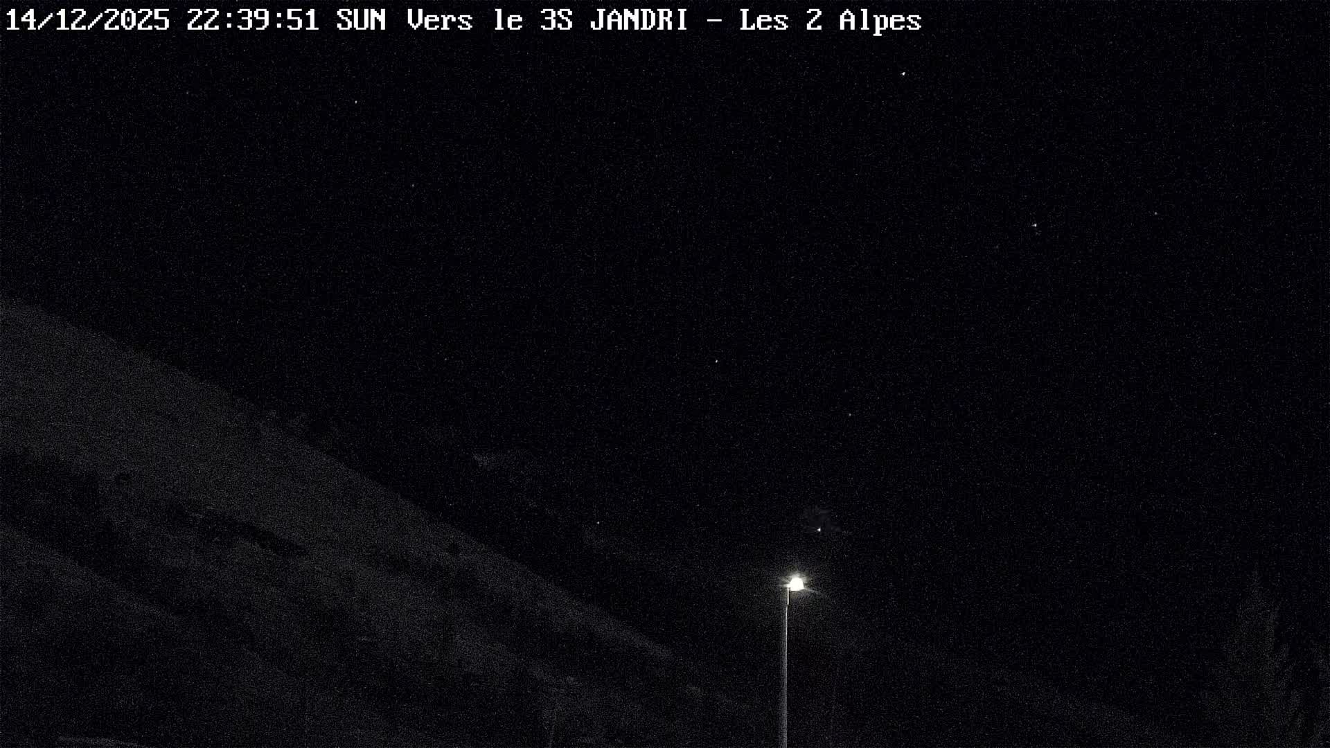 A snowy mountain slope, dotted with bare trees and evergreens, features multiple ski lifts traversing the landscape under a uniformly grey, overcast sky.