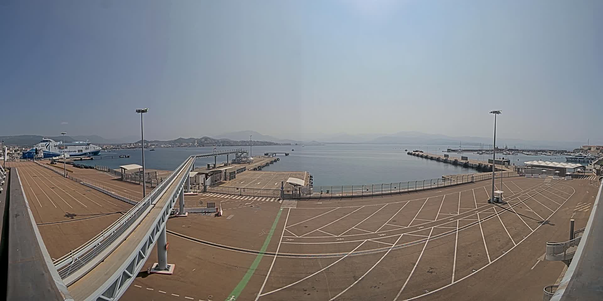 An empty ferry terminal with a docked ferry and a clear, sunny day.