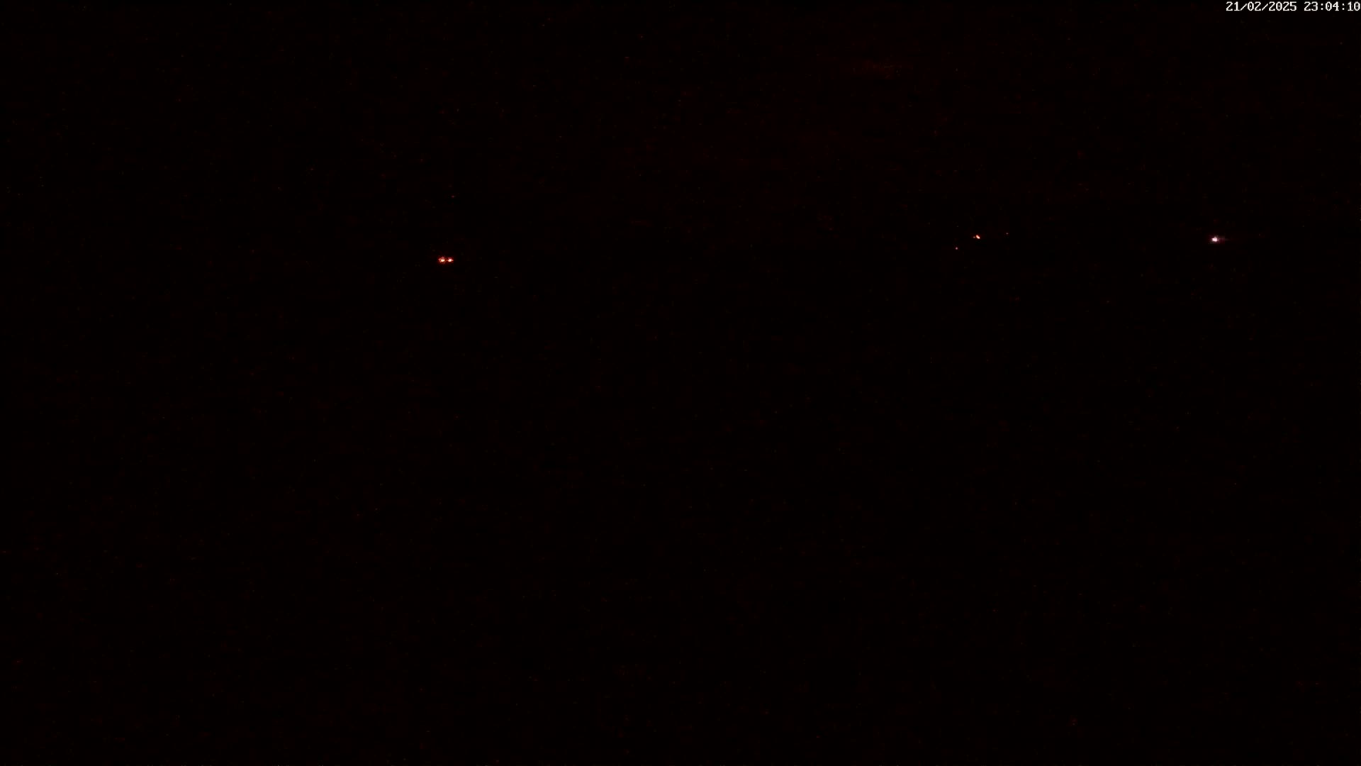 Three faint red lights are visible in the dark night sky.