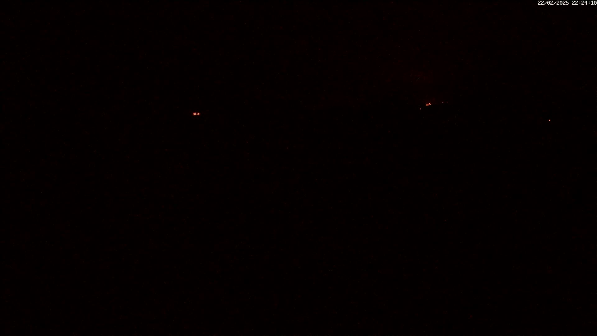 A nighttime view shows three faint reddish lights in the distance against a completely dark sky.