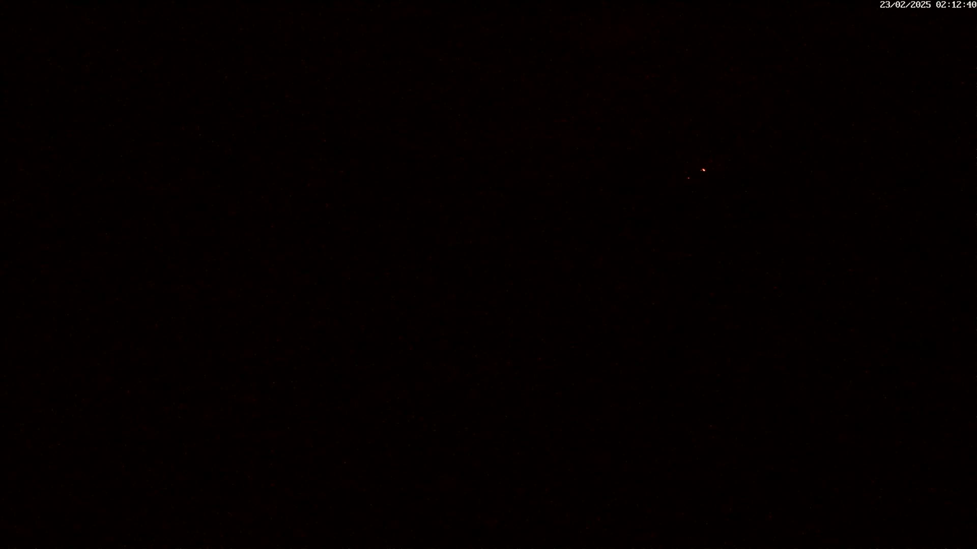 A dark, nighttime scene with a faint, reddish light source visible in the distance.