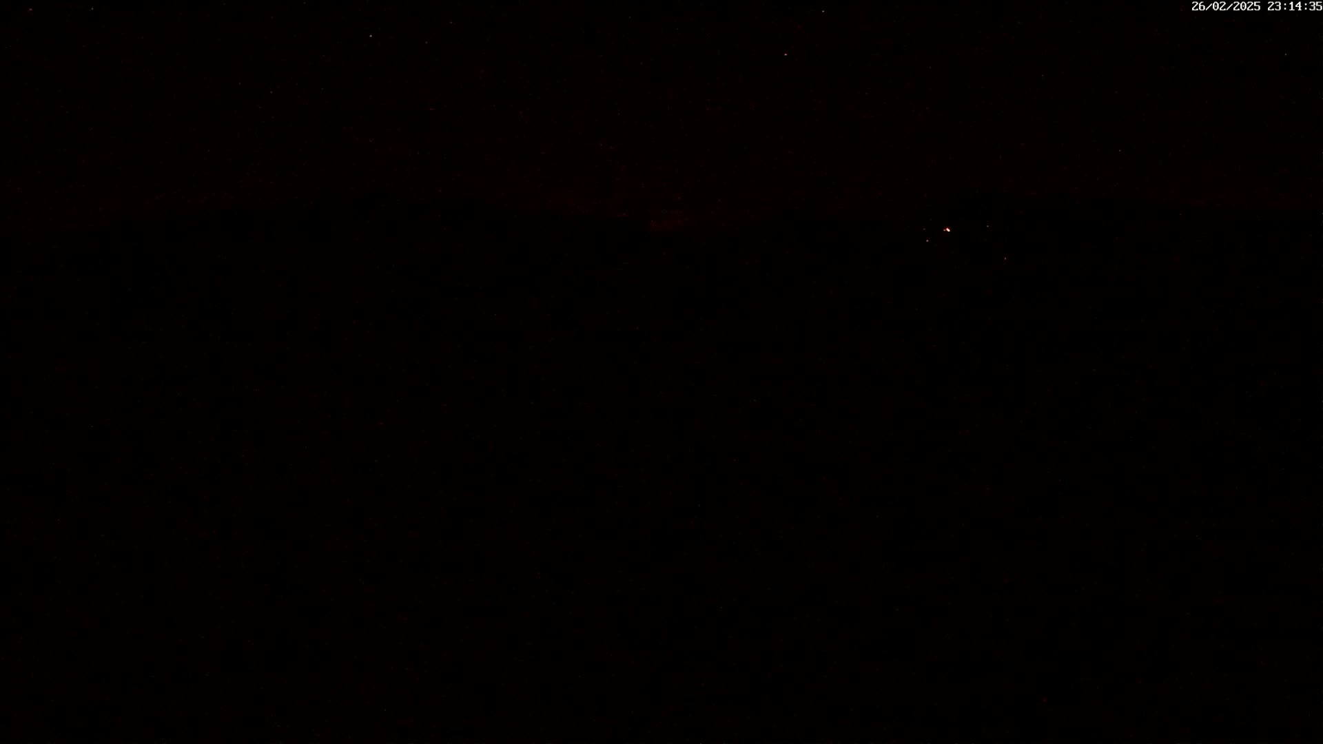 A nighttime outdoor scene shows a dark sky with a few faint stars and a small, distant light source.