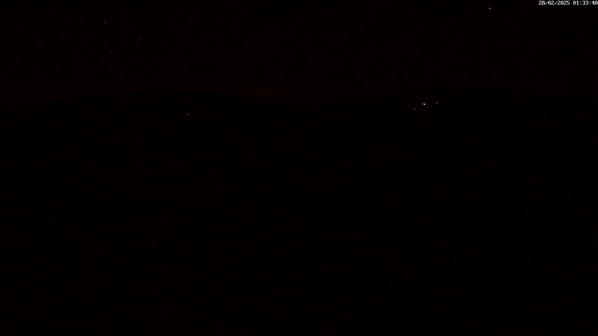 A nighttime, dark scene with a few faint, distant lights visible in the sky.