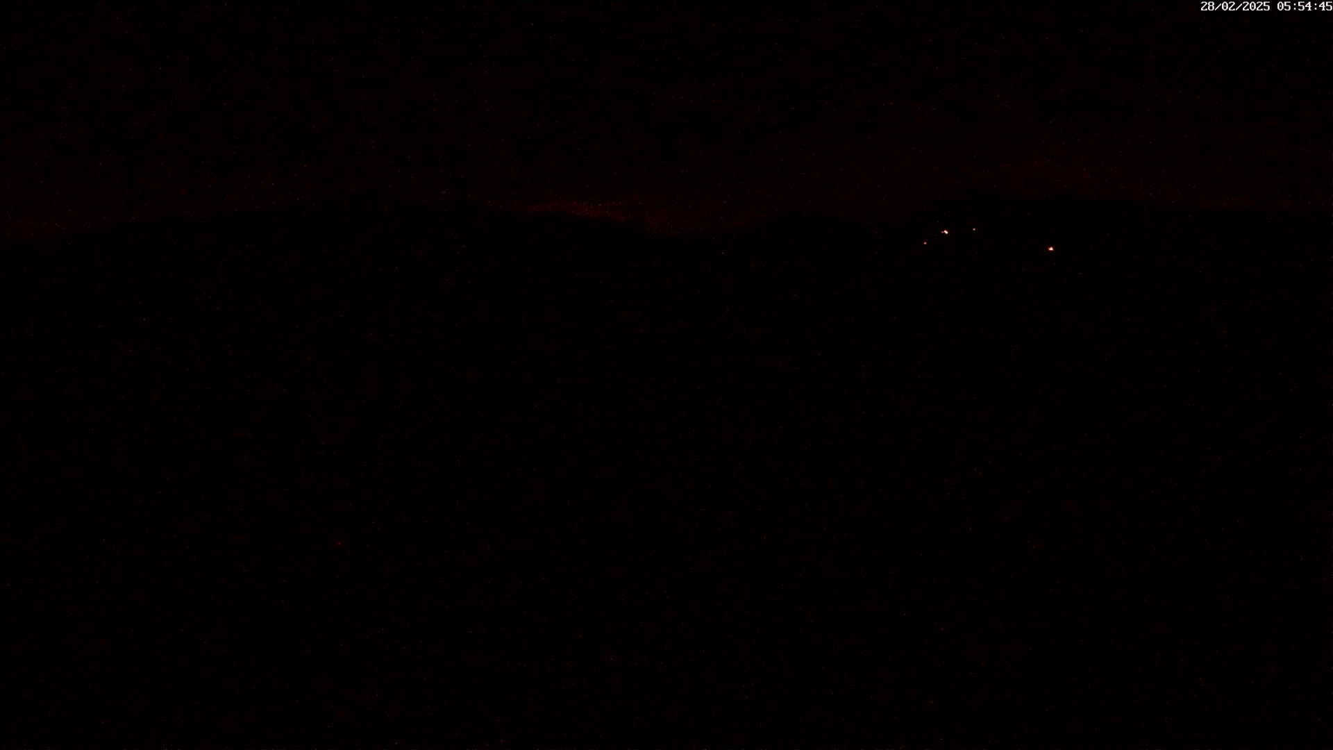 A dark, nighttime scene shows a few faint, distant lights on the horizon.