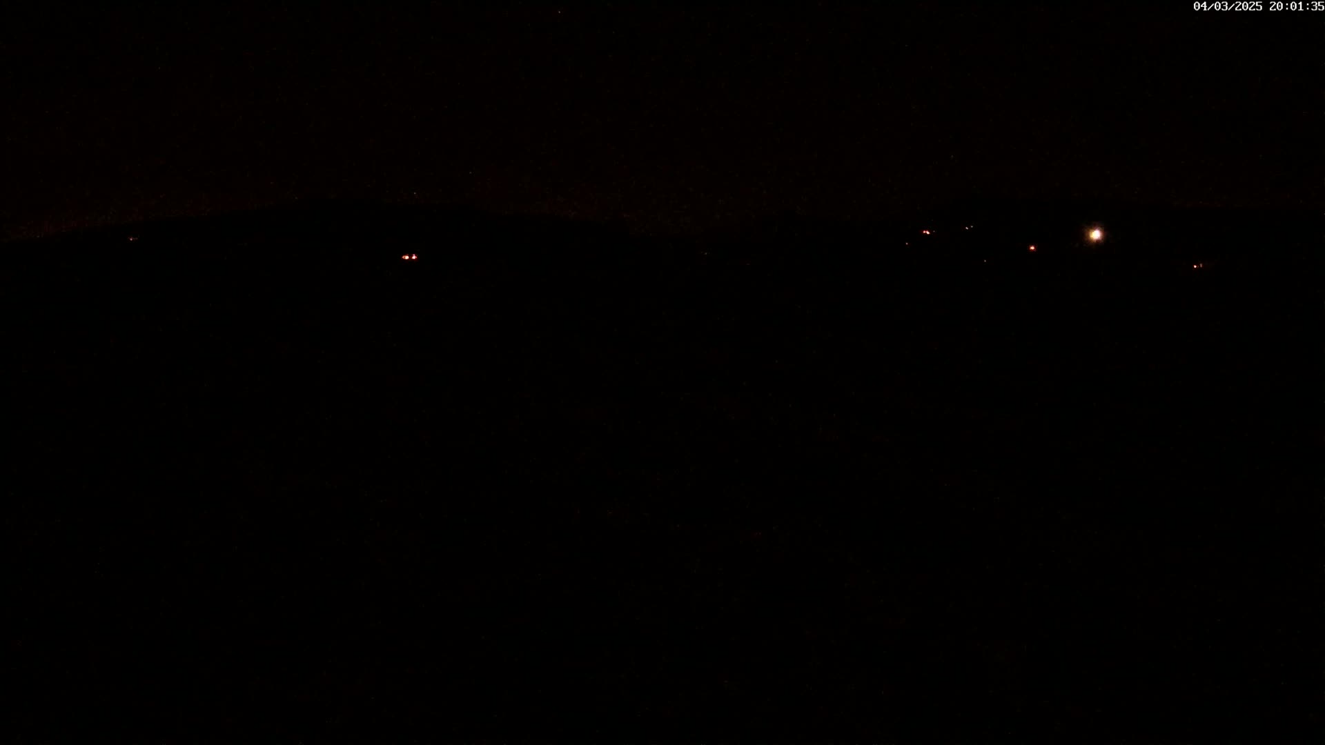 A nighttime, dark scene with a few distant, faint lights visible.
