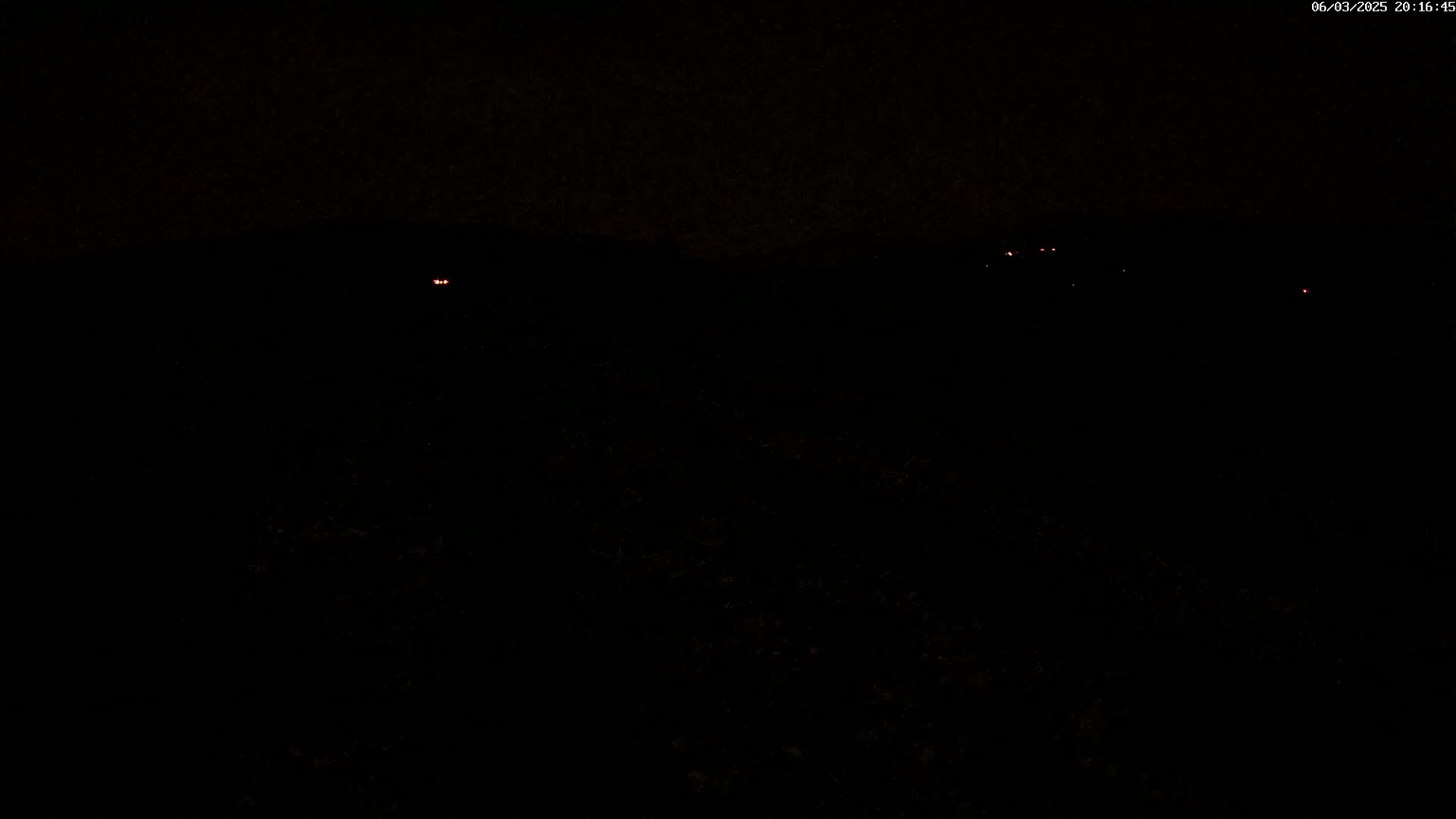 A nighttime, dark landscape with a few faint, distant lights visible.