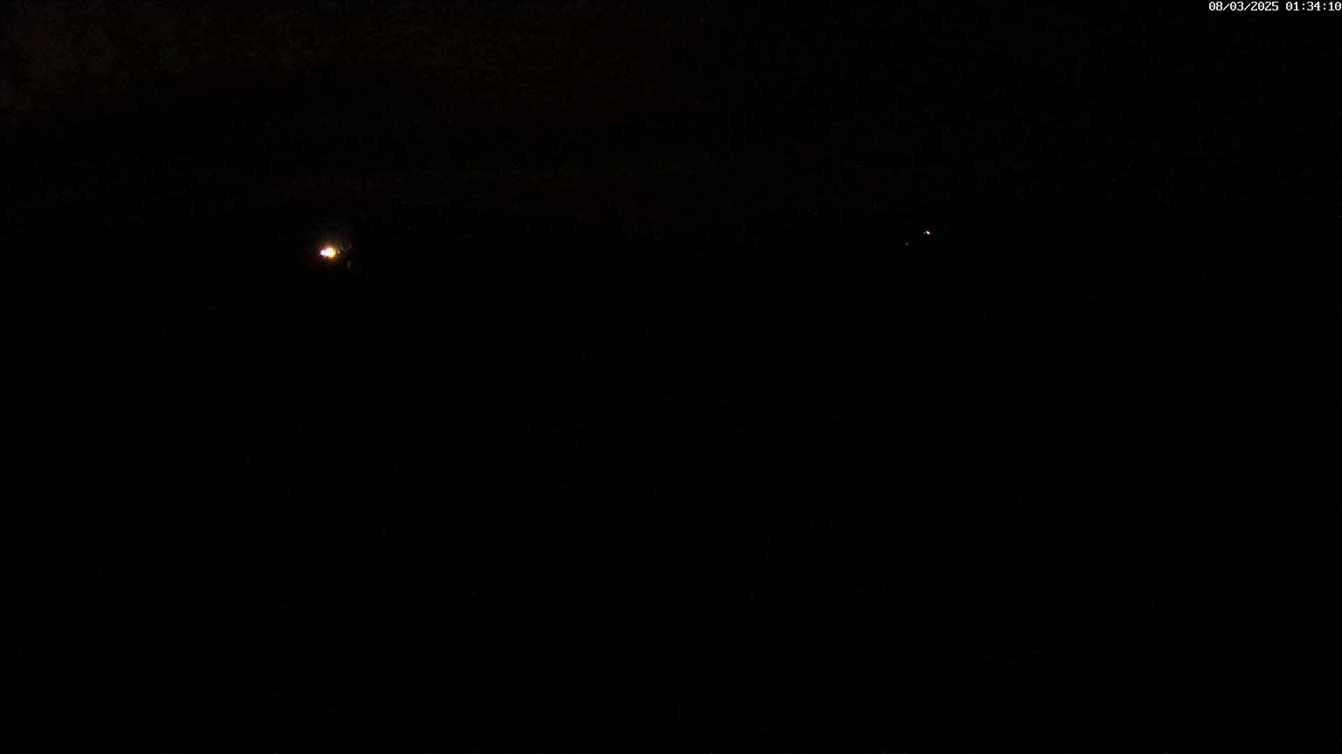 A dark nighttime scene shows two small, distant lights in an otherwise black sky.