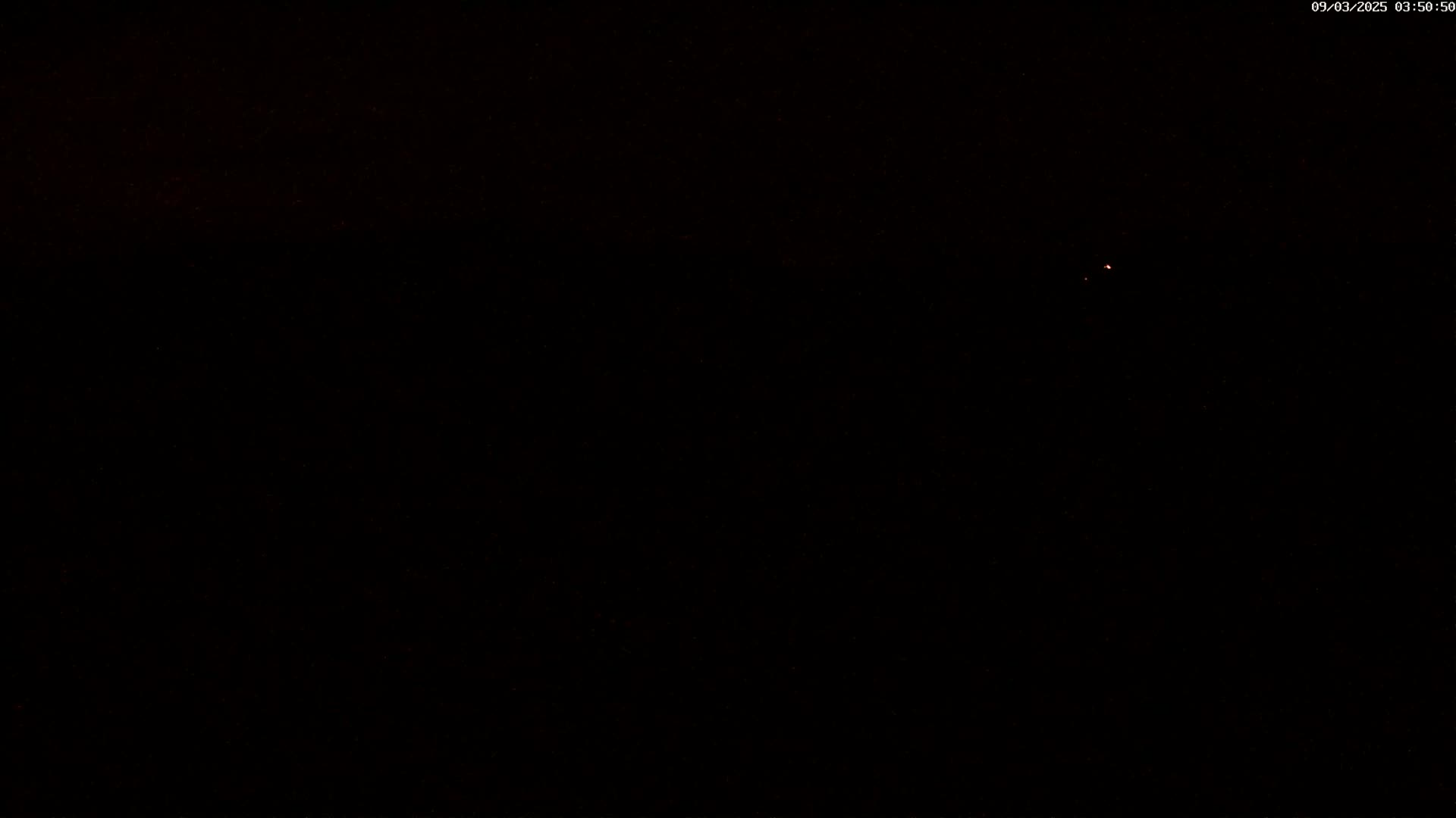 A dark nighttime scene shows a single, faint light in the distance.