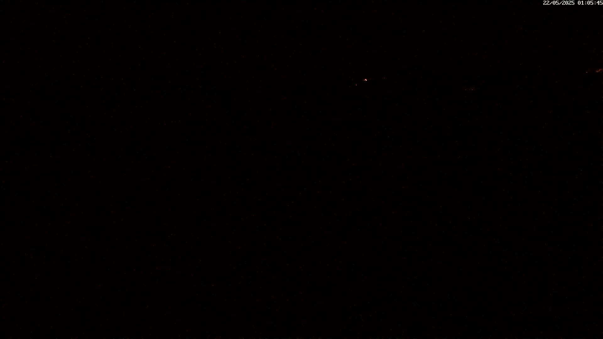 A very dark image shows a few faint orange lights in the distance at night.