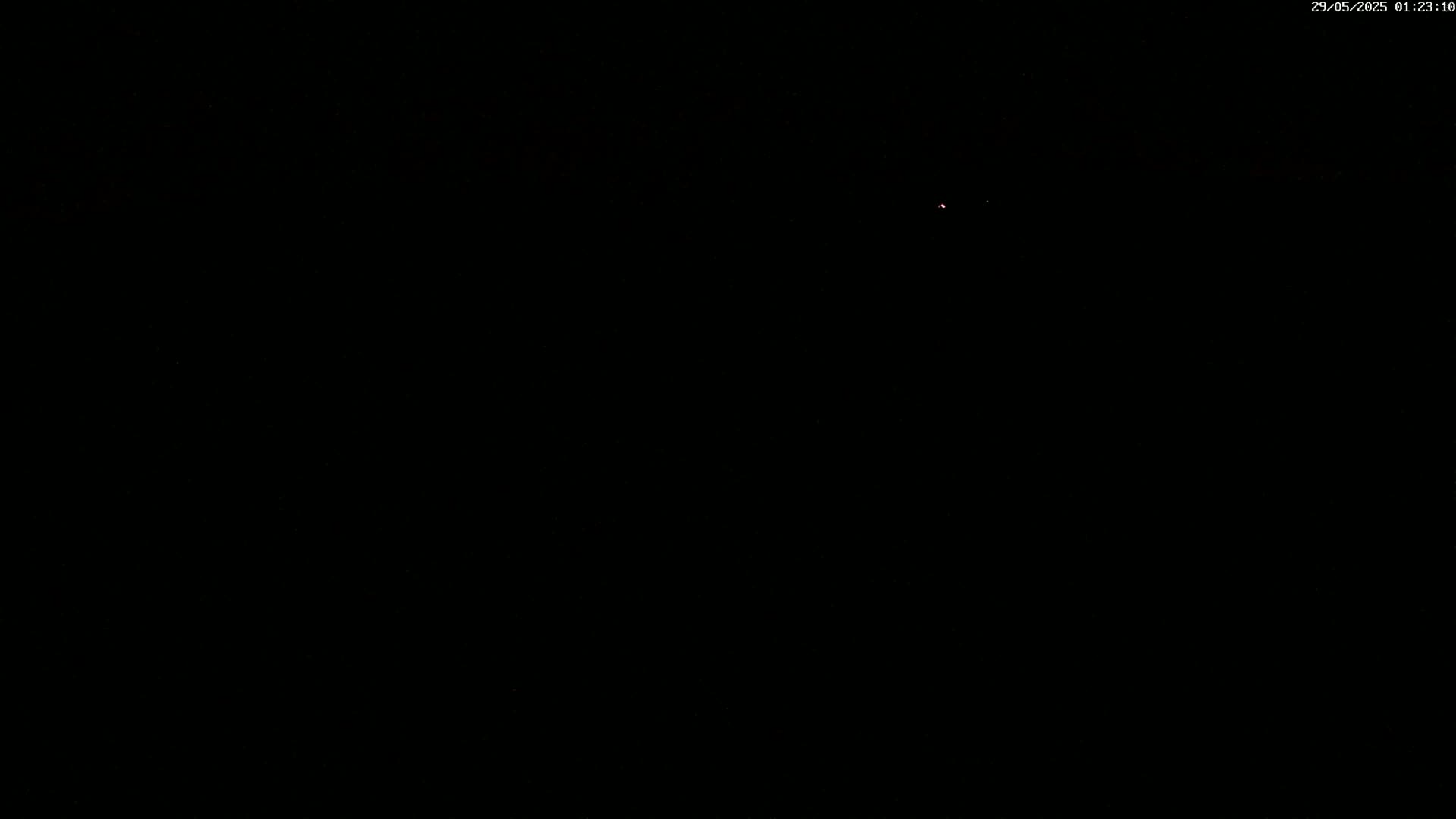 A single, faint light is visible in a dark, nighttime sky.
