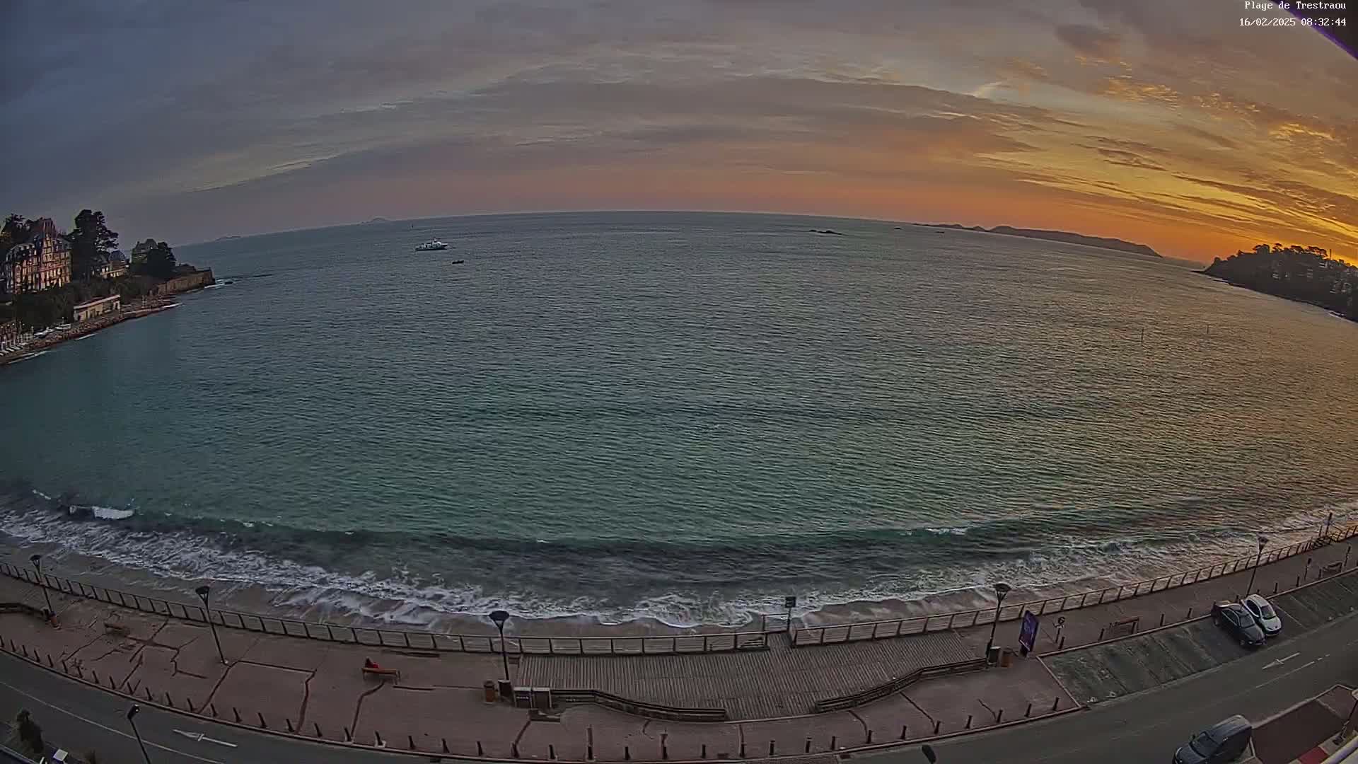 A seaside boardwalk with a calm ocean under a sunset sky.