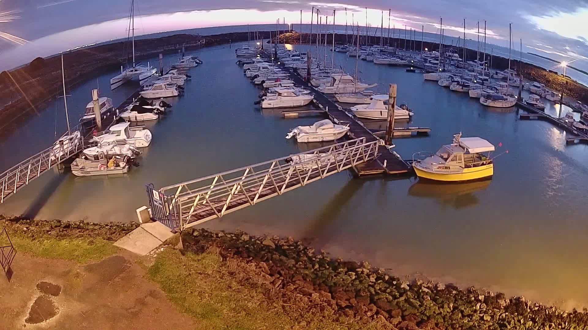 A marina filled with numerous boats at dusk, under a mostly clear sky.