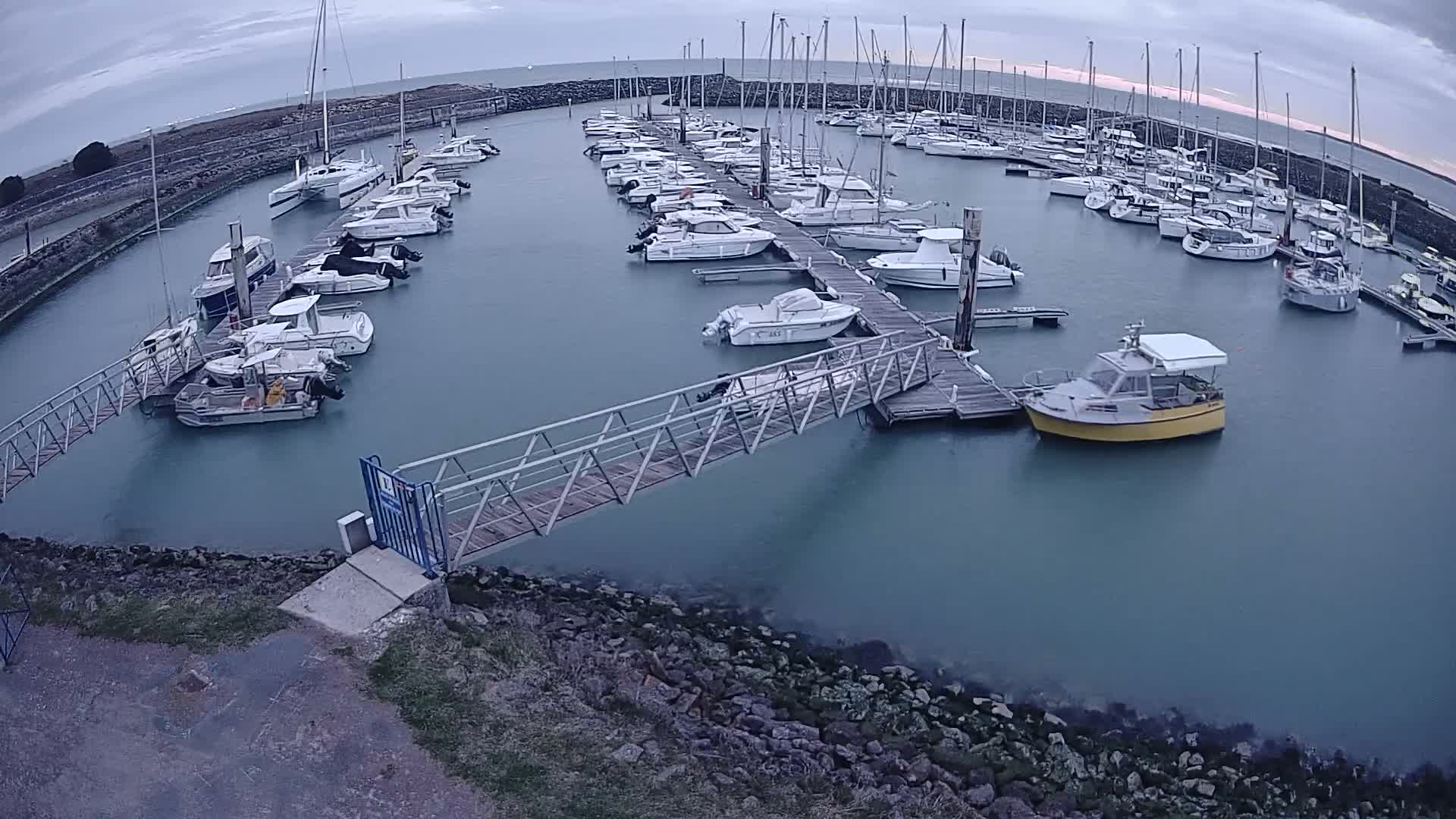 A marina filled with numerous boats and yachts under an overcast sky.