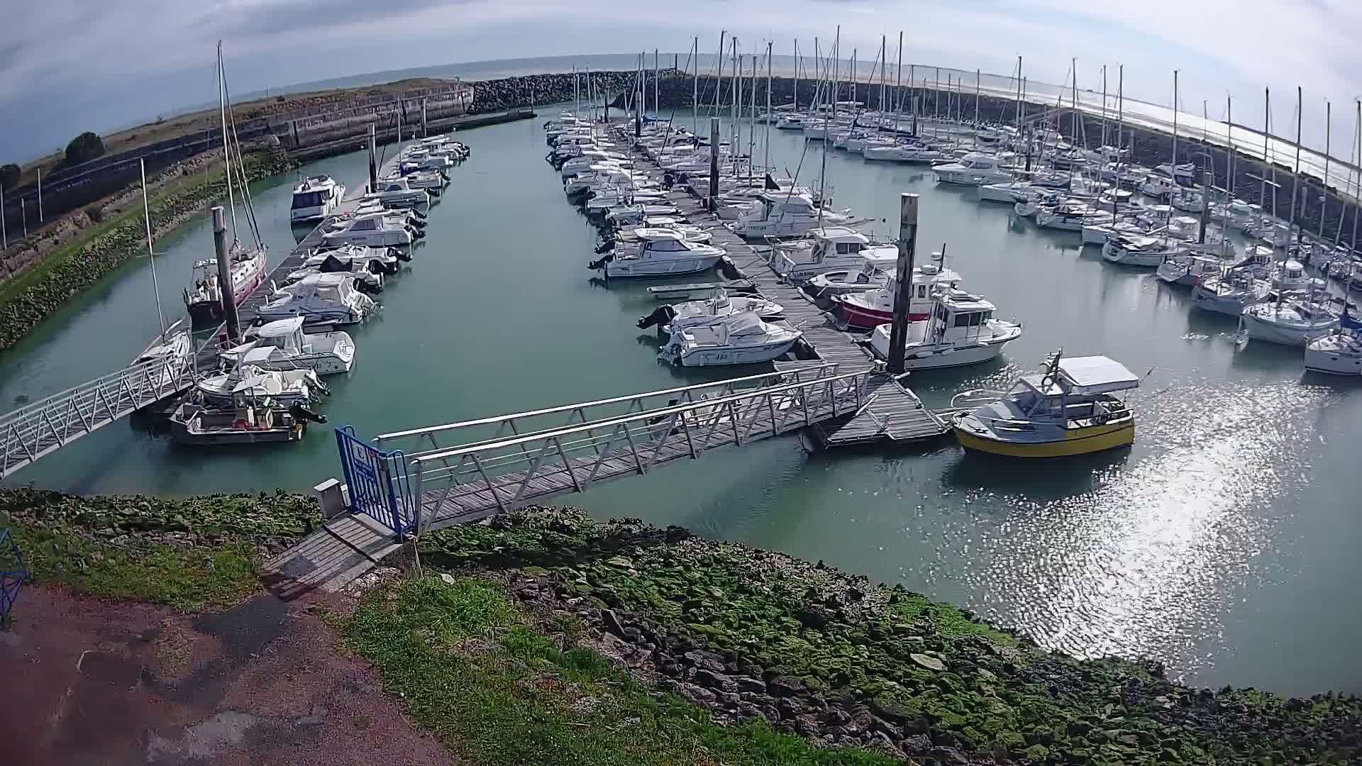 A marina filled with numerous boats of various sizes under a mostly sunny sky.