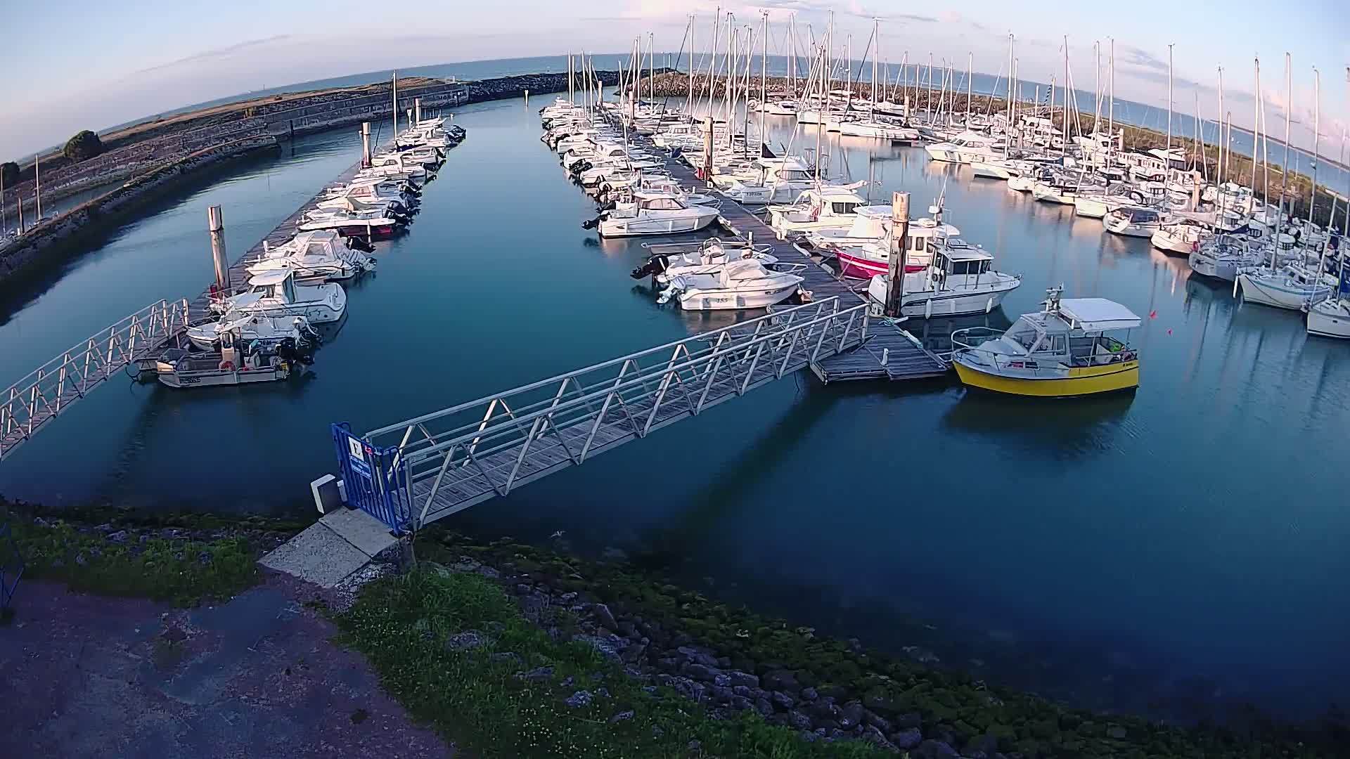 A marina filled with numerous boats docked along piers under a mostly clear sky.