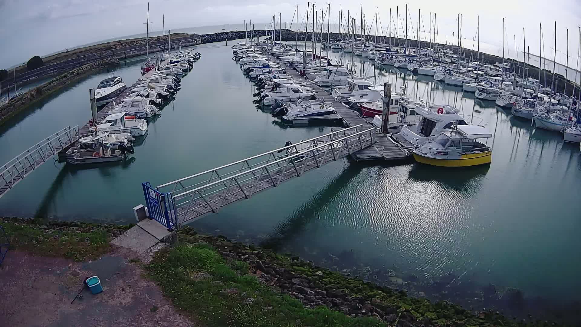 A marina filled with numerous sailboats and motorboats on a cloudy day.