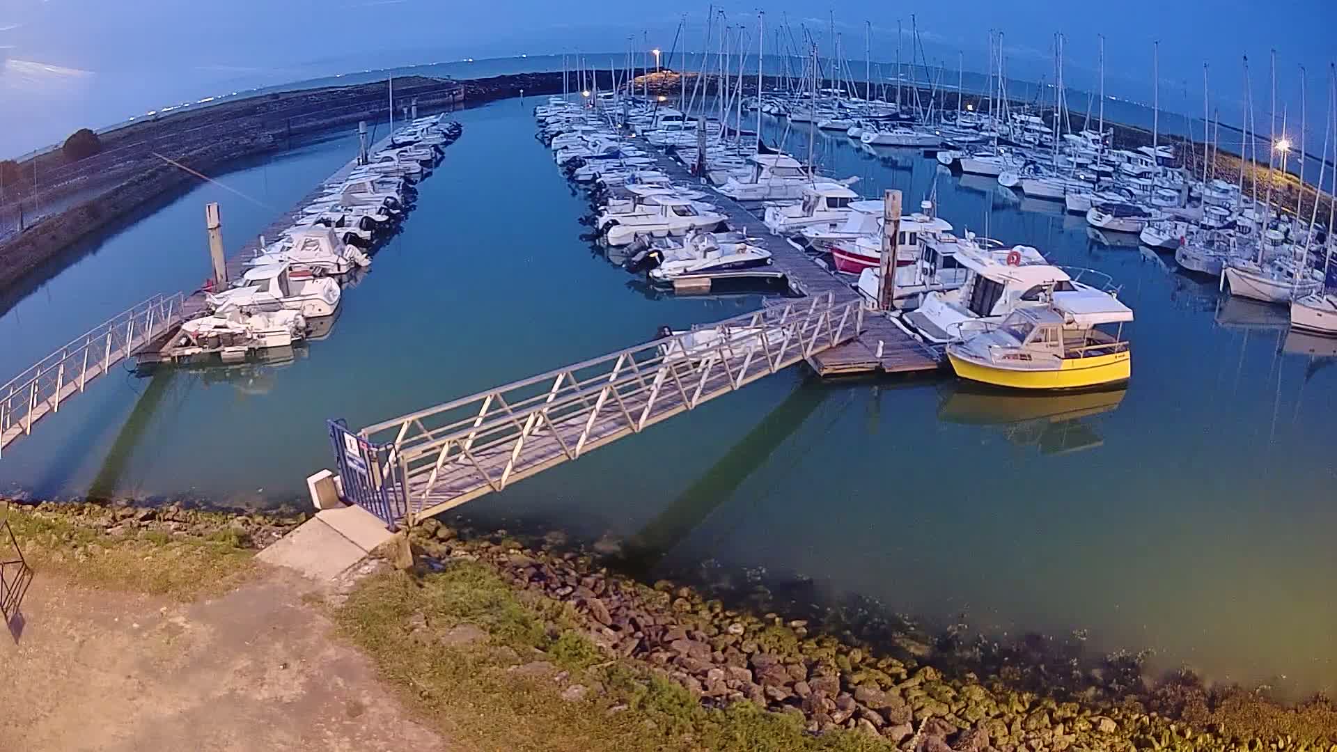 Many boats are docked at a marina under a twilight sky.