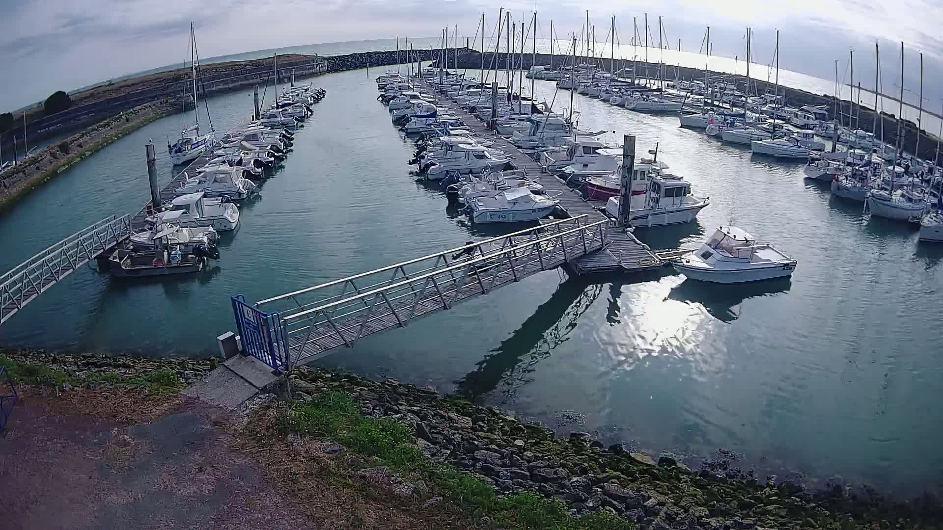 A marina filled with numerous boats on a partly sunny day.