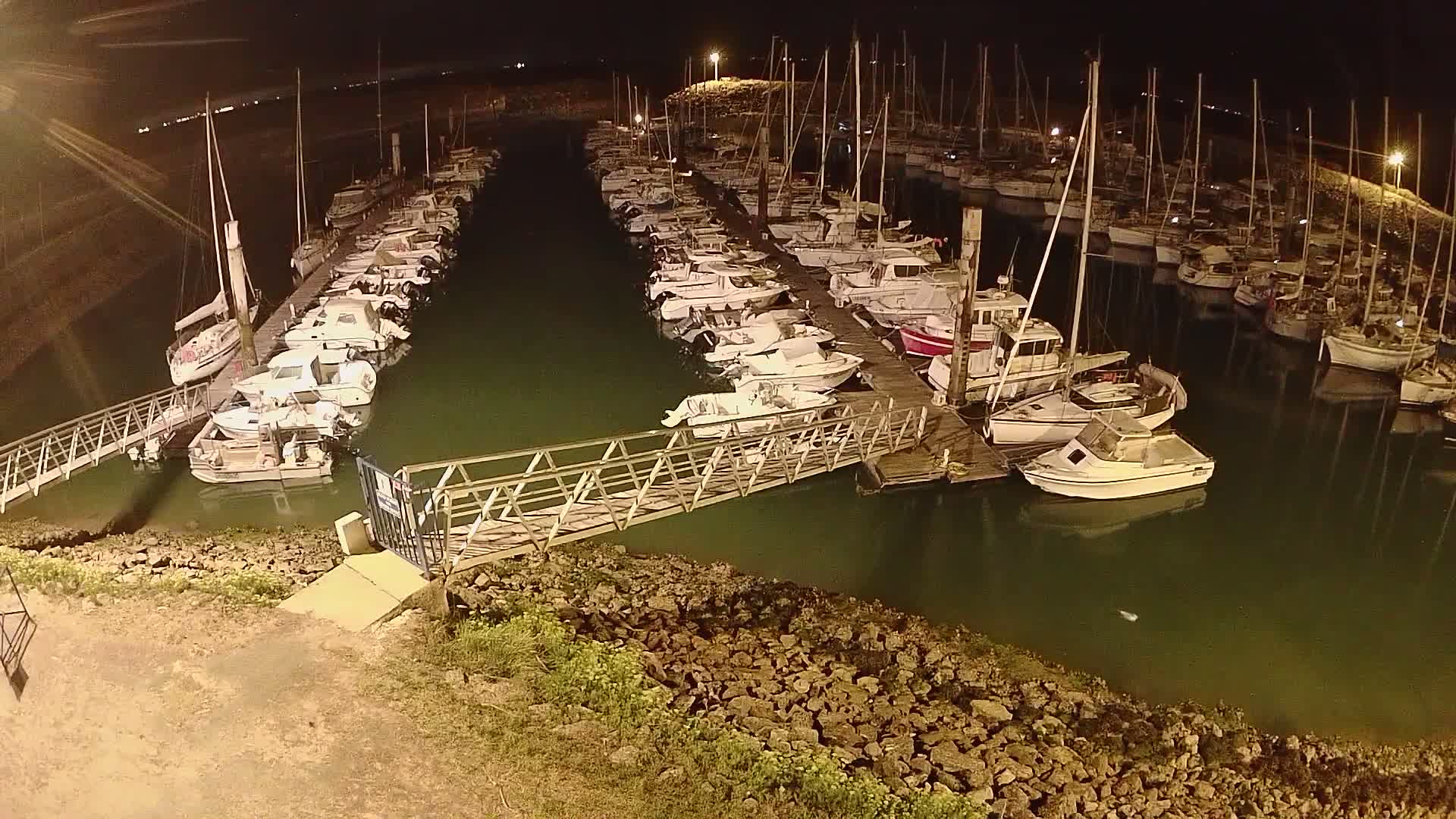 A marina filled with numerous boats and sailboats under a cloudy sky.