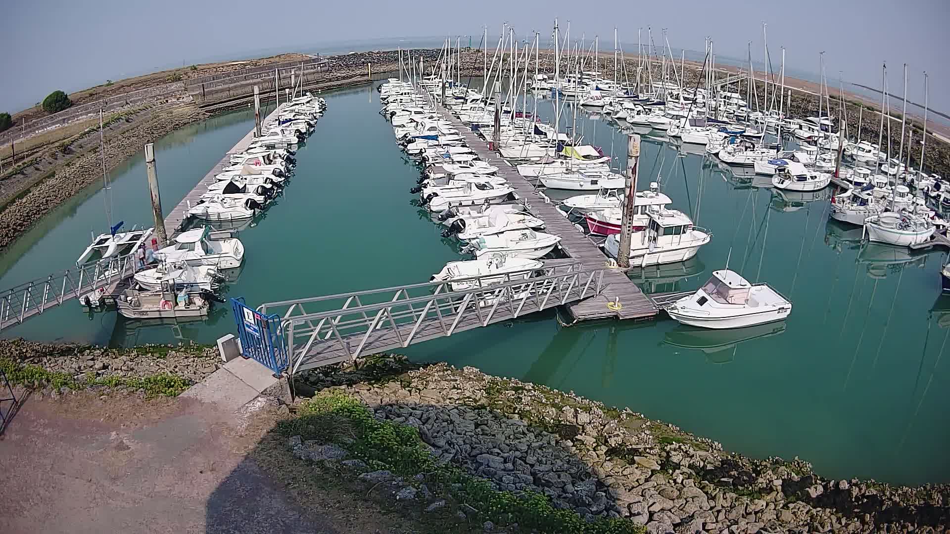 A marina filled with numerous boats and sailboats under a cloudy sky.