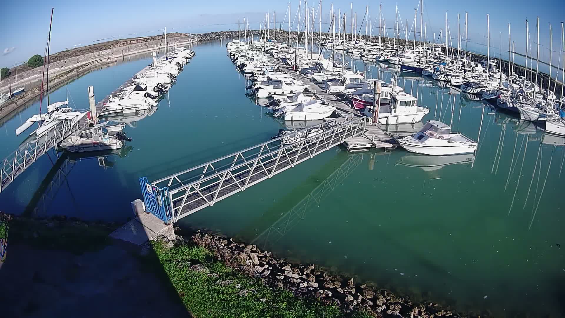 A marina filled with numerous boats and sailboats under a cloudy sky.