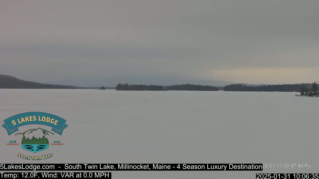 A frozen lake stretches to a treeline under an overcast sky.