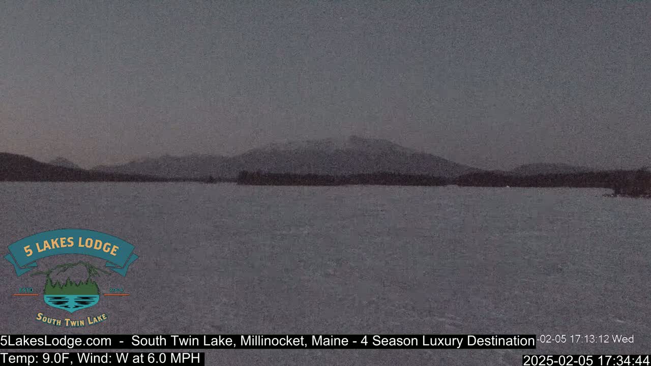 A dark, still lake is visible under a dusky sky, with mountains in the background.