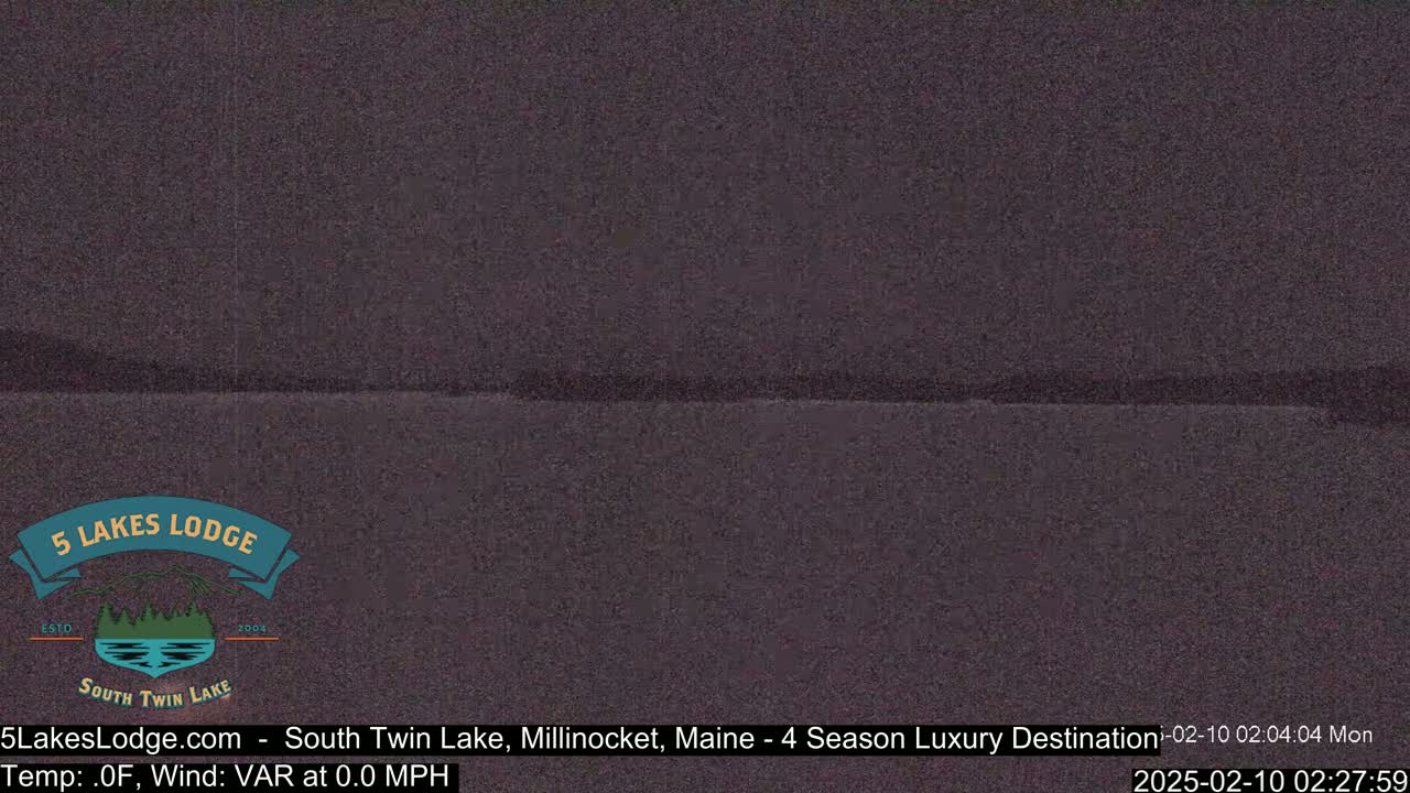A dark, still body of water is seen under a night sky.