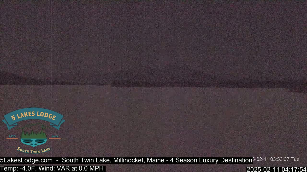 A dark, still body of water is visible under a dark, overcast sky.