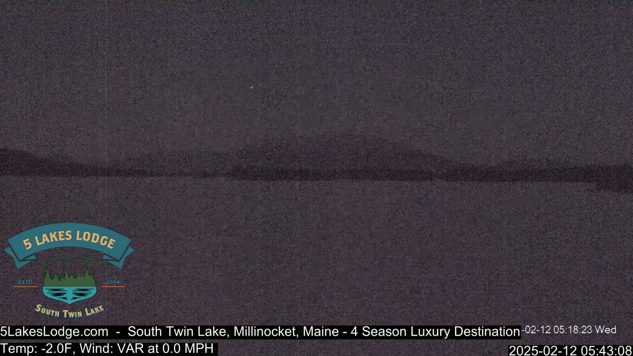 A dark, nighttime view of a lake with a distant, barely visible shoreline under a clear sky.