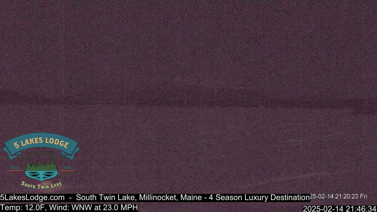 A dark, nighttime view of a still body of water under a cloudy sky.