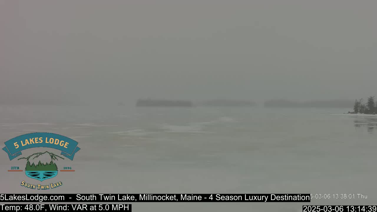 A hazy, gray view of a lake with a distant shoreline and some small islands under foggy conditions.
