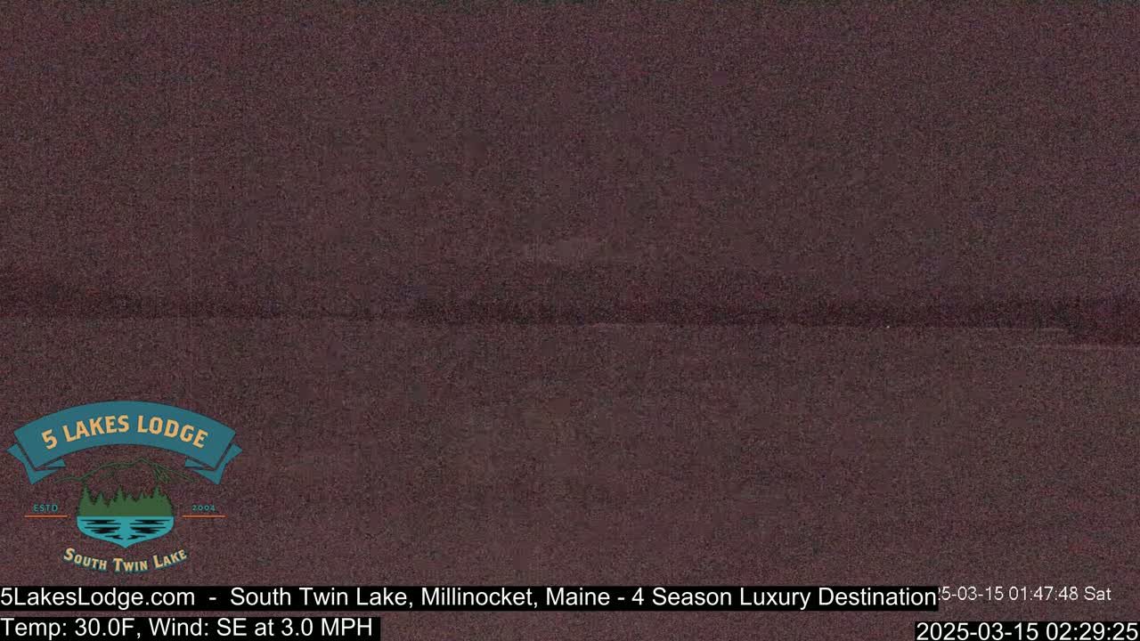 A dark, nighttime view of a lake under a cloudy sky, with a slight southeast wind.