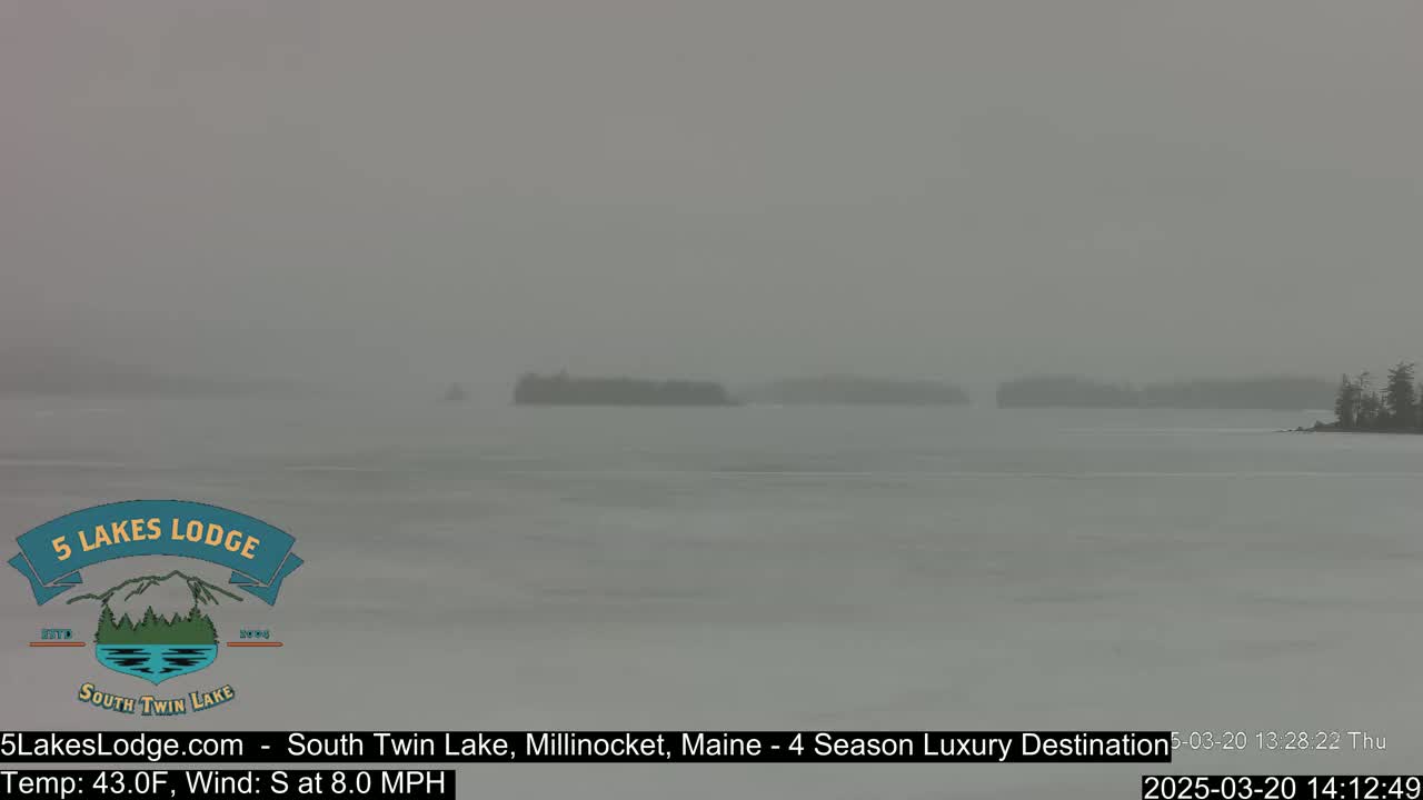 A snow-covered lake with distant, indistinct islands is visible under hazy, snowy conditions.