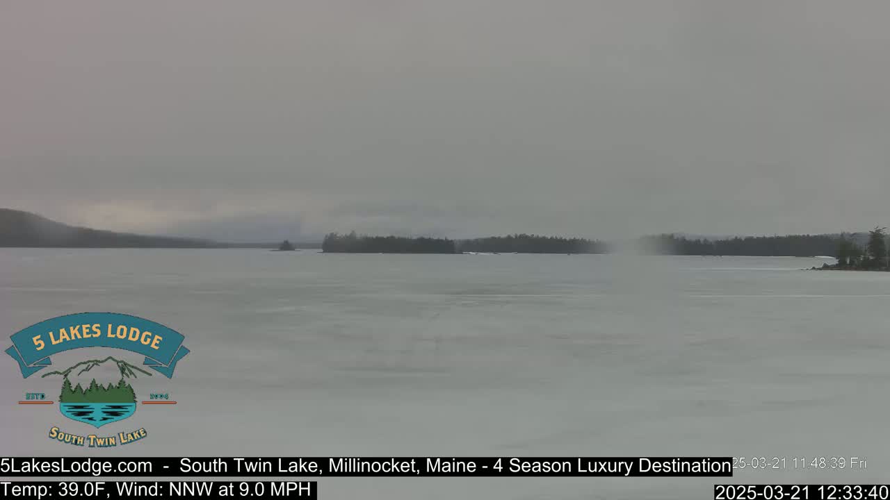 A mostly frozen lake is visible under an overcast sky.