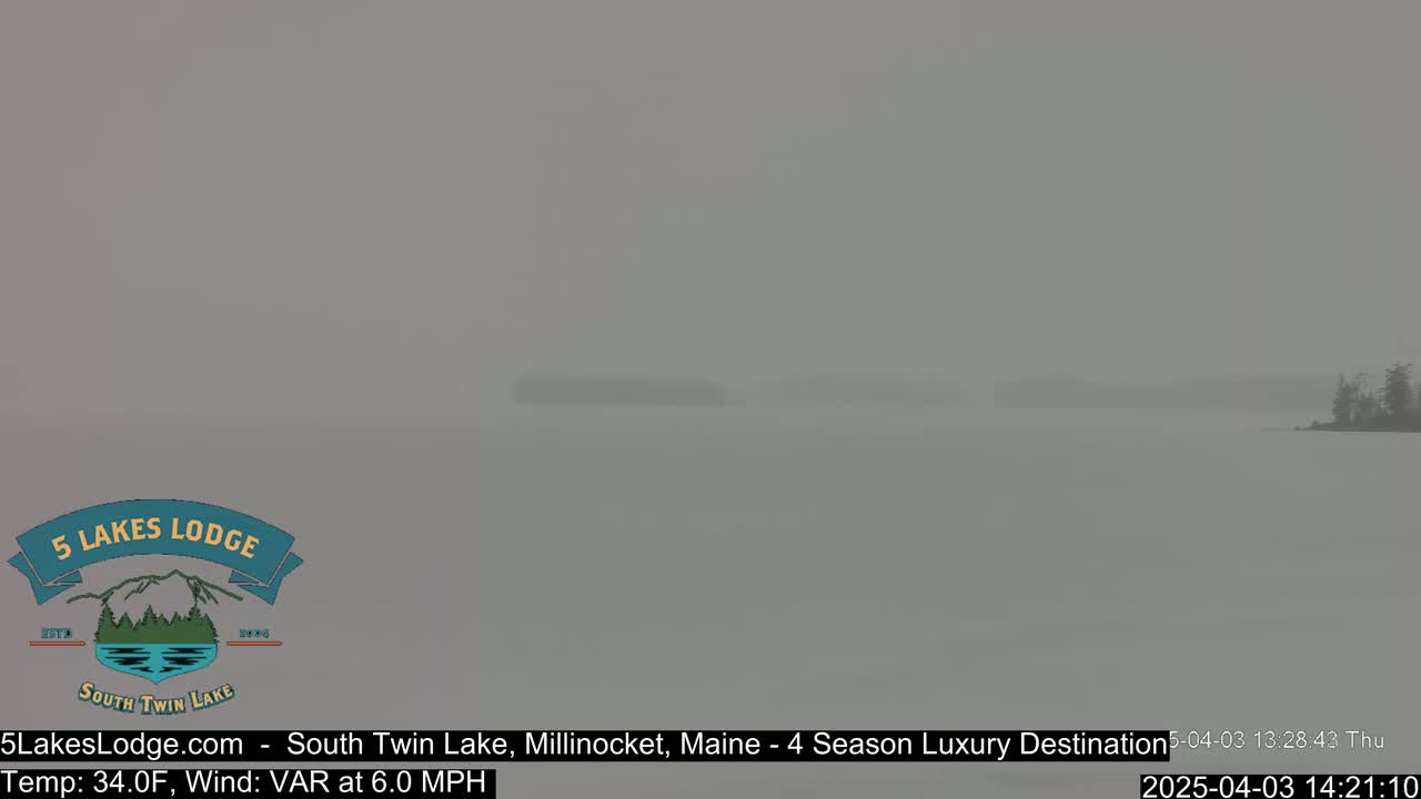 A hazy, gray lake is visible with a dark shoreline in the distance, under overcast conditions.