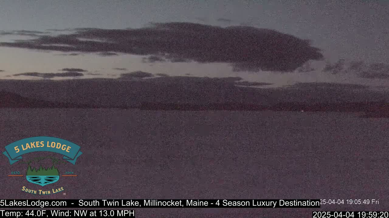 A calm lake is visible under a mostly cloudy, twilight sky.